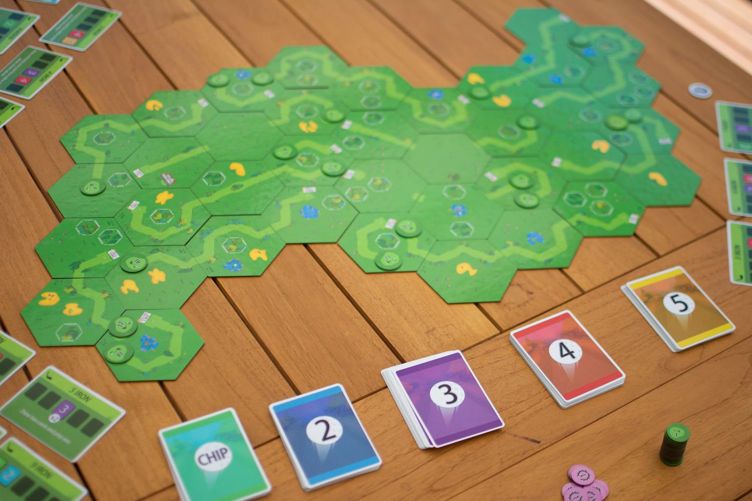18 Holes game setup on a table. A course has been laid out with the modular tiles and the shot decks have been setup beside the board